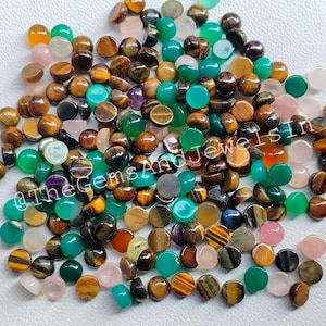 May include: A collection of assorted cabochon gemstones in various colors, including green, brown, pink, and purple. The gemstones are round and have a smooth, polished finish. They are ideal for jewelry making or other craft projects.