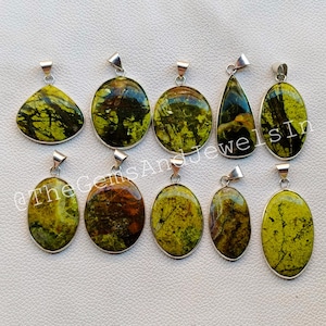 Puede incluir: Una colección de diez colgantes de piedras preciosas en varias formas, incluyendo ovaladas y de lágrima. Los colgantes presentan tonos verdes y marrones, con colgadores de metal plateado. El texto "@TheGemsAndJewelsIn" es visible.