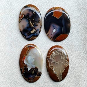 May include: Four oval-shaped agate cabochons with brown, black, white, and gray patterns. The cabochons are polished and have a smooth, glossy finish.