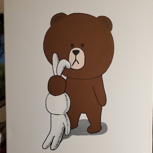 May include: A brown bear with a white rabbit in its hand. The bear is looking at the rabbit with a serious expression. The rabbit is holding its paws up in the air.
