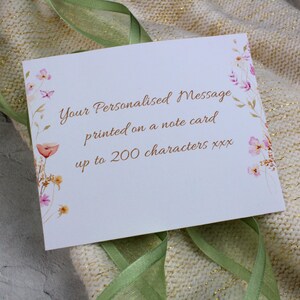 Peut inclure: Une carte blanche avec un motif floral et le texte "Your Personalised Message printed on a note card up to 200 characters xxx".