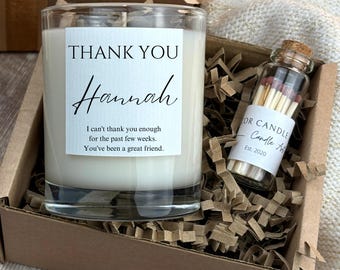 May include: A gift set in a cardboard box containing a clear glass candle with a white label reading THANK YOU Hannah I can't thank you enough for the past few weeks. You've been a great friend. and a small glass vial of matches.