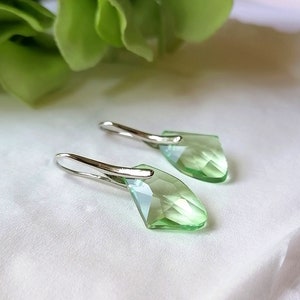 May include: A pair of silver dangle earrings with light green faceted crystal drops.