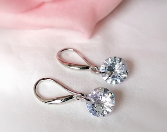 May include: A pair of silver dangle earrings with clear round crystal stones.