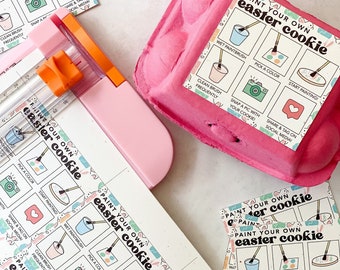 May include: A set of printable Easter cookie decorating instructions. The instructions are printed on white cardstock and feature a colorful design with bunnies and eggs. The instructions include steps like "wet paintbrush", "pick a color", "start painting", "clean brush frequently", "snap a pic with your cookie", and "share & tag on social media".