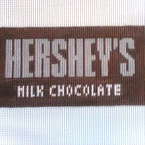 May include: A brown rectangular label with white text that reads "HERSHEY'S MILK CHOCOLATE".