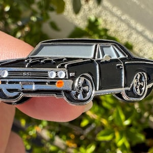 May include: Black enamel pin of a classic black Chevrolet muscle car with chrome accents and the text "SS" on the front grill.