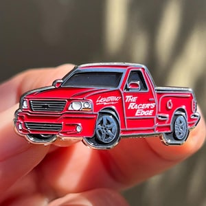 Puede incluir: Pin de esmalte de camioneta Ford F-150 Lightning roja con la inscripción "The Racer's Edge" en el lateral.