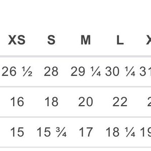 May include: A chart displaying clothing measurements in inches. The chart includes body length, body width, and sleeve length measurements for sizes XS through 4XL. The body length ranges from 26 1/2 to 34 1/2 inches.