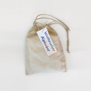 May include: A white drawstring bag with a tag that says "Watercolor Alphabet".