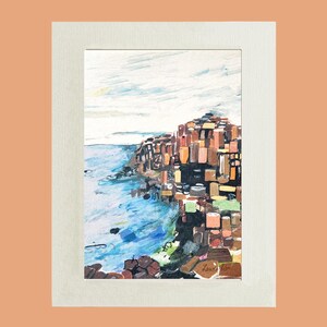 May include: A watercolor painting of a rocky cliffside with a blue ocean in the foreground. The cliff is made up of many small, rectangular shapes in shades of brown, orange, and green. The sky is a light blue with white clouds. The painting is signed "Laurie 1990" in the lower right corner.