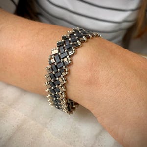 Könnte beinhalten: Ein Armband aus schwarzen und silbernen Perlen mit einem Chevron-Muster.