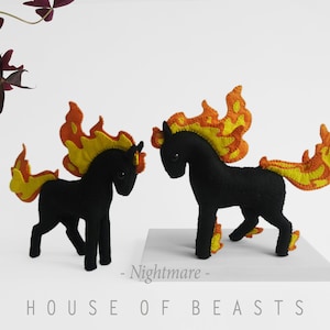 Può includere: Due giocattoli a forma di cavallo in feltro nero con fiamme in feltro arancione e giallo per criniere e code. Il testo "Nightmare" e "House of Beasts" è stampato sotto i giocattoli.