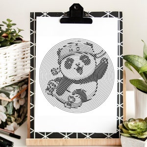 May include: Black and white art print with a spiral design. The artwork is displayed on a clipboard with a black and white geometric border. The print is held in place by a black clip.