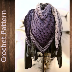 Peut inclure: Un châle en crochet violet et gris avec un motif ajouré. Le châle est drapé sur une veste en cuir noir et un mannequin.