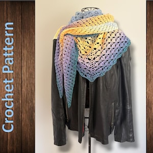 Op de afbeelding: Een driehoekige gehaakte sjaal met een kleurverloop van lichtblauw naar geel en paars, gedrapeerd over een zwart leren jack. De tekst "Crochet Pattern" is verticaal in lichtblauw aan de linkerkant van de afbeelding gedrukt.