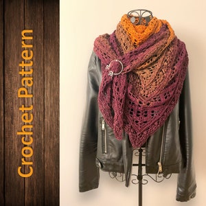 Peut inclure: Un châle en crochet dans des tons de bordeaux, marron et orange. Le châle est drapé sur une veste en cuir noir et possède un fermoir métallique décoratif.