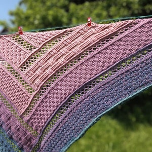 Puede incluir: Un chal de ganchillo con un degradado de colores rosa, morado y azul. El chal est&aacute; hecho con un delicado patr&oacute;n de punto y tiene un borde con flecos.