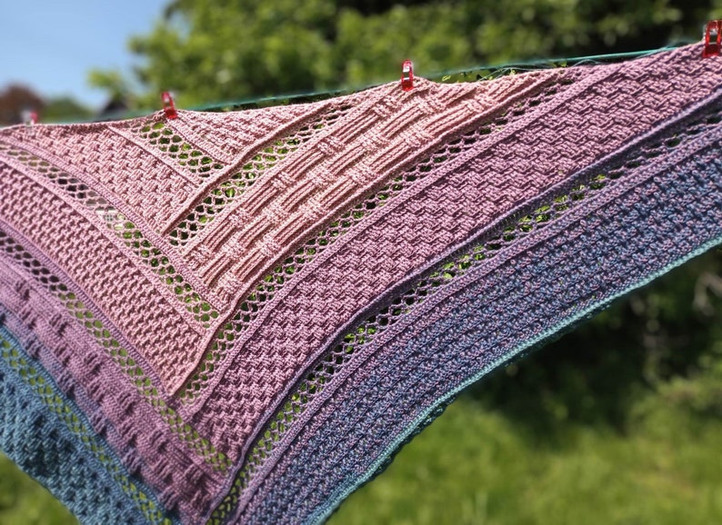 Puede incluir: Un chal de ganchillo con un degradado de colores rosa, morado y azul. El chal est&aacute; hecho con un delicado patr&oacute;n de punto y tiene un borde con flecos.