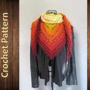 Op de afbeelding: Een driehoekige gehaakte sjaal met een kleurverloop van crème naar geel, oranje, rood en donkerbordeaux. De sjaal heeft een ingewikkeld opengewerkt kantpatroon en is gedrapeerd over een zwart jasje. De tekst Crochet Pattern is zichtbaar.