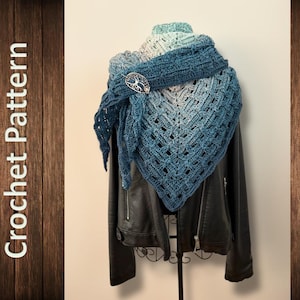 Peut inclure: Un châle crocheté bleu et gris avec un fermoir arbre de vie, présenté sur une veste en cuir noire. Le châle présente un motif ajouré géométrique. Le texte "Crochet Pattern" est sur le côté gauche de l'image.