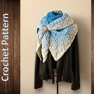 May include: A crocheted shawl in shades of blue and white, with a delicate lace pattern. The shawl is draped over a black leather jacket, creating a stylish and cozy look.