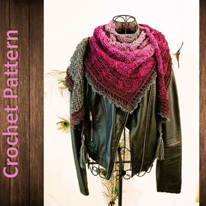 Könnte beinhalten: Ein gehäkeltes Tuch mit einem Farbverlauf von Rosa, Lila und Grau. Das Tuch hat eine zarte Spitzenborte und einen Quasten an einem Ende. Das Tuch ist über eine schwarze Lederjacke gelegt.
