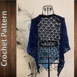 May include: A blue crocheted shawl with a lacy pattern, displayed on a black mannequin. The shawl is draped over the mannequin's shoulders and hangs down to the mannequin's waist.