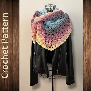 May include: A multi-coloured, crocheted shawl in pink, yellow, blue, and purple is draped over a black leather jacket. The shawl has an open, lacy design. The words "Crochet Pattern" are visible on the left side of the image.