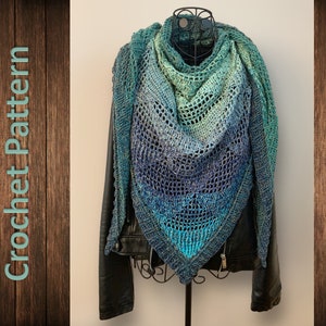 May include: A crocheted shawl in shades of blue and green, with a lacy pattern. The shawl is draped over a black leather jacket, and is displayed on a mannequin.