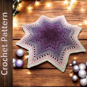 Könnte beinhalten: Ein gehäkelter Stern in Lila-, Lavendel- und Cremetönen mit aufwendigen Lochmusterdetails. Der Stern liegt auf einer Holzoberfläche, umgeben von silbernen Kugeln und Lichterketten. Der Text "Crochet Pattern" befindet sich links.