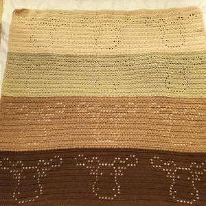 May include: A crocheted blanket with a multi-colored striped pattern. The blanket is made of brown, beige, and green yarn. The blanket has a lacy design with open spaces.