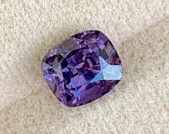 May include: A cushion-cut purple gemstone with a faceted surface.