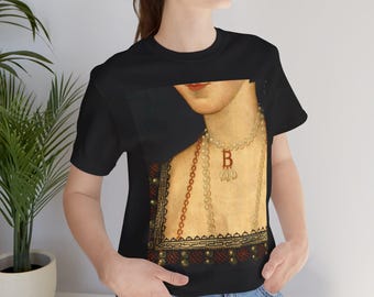 Pode incluir: T-shirt preto com um retrato em estilo renascentista. O retrato mostra uma mulher com um colar de pérolas e um pingente com a letra "B". O design inclui uma borda decorativa com detalhes vermelhos e dourados. Gola redonda.
