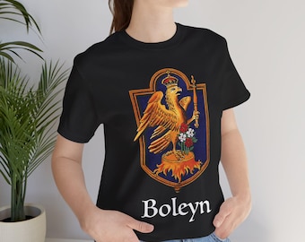 Pode incluir: T-shirt preta com um design de brasão detalhado. O brasão apresenta uma águia dourada, uma coroa e um cetro sobre um fundo azul. A palavra "Boleyn" está impressa em branco abaixo. O design está centrado na camiseta.