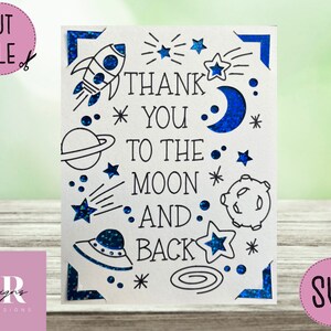 Op de afbeelding: Een witte kaart met een blauwe glitterrand en een ruimtethema. De kaart zegt "Bedankt tot de maan en terug" met sterren, planeten, een raket en een UFO.