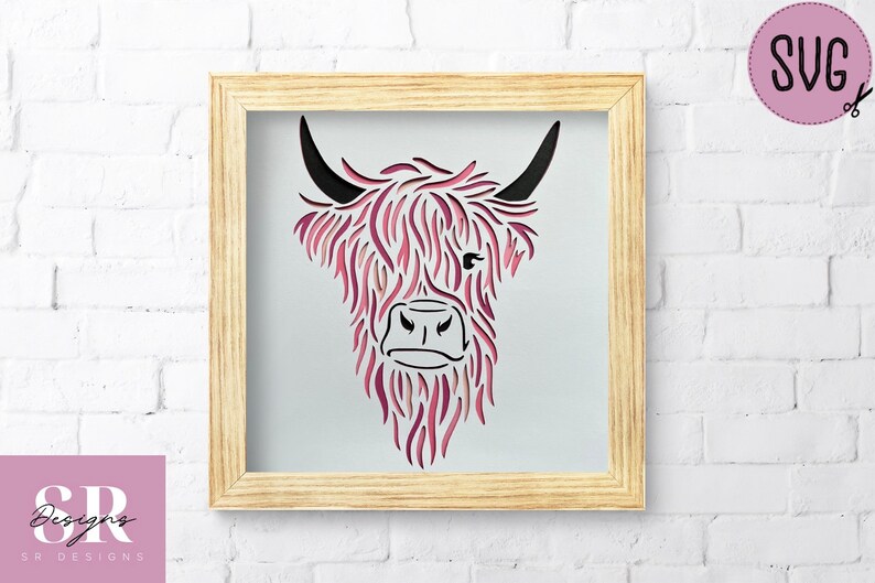 Puede incluir: Un archivo de corte digital de una cabeza de vaca Highland con colores rosa y negro. La cabeza de la vaca est&aacute; enmarcada en un marco de madera claro.
