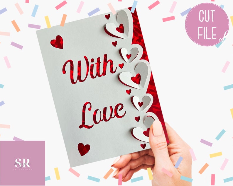 Pu&ograve; includere: Un biglietto bianco con le parole "With Love" in scrittura rossa. Il biglietto ha un bordo decorativo di cuori rossi e bianchi.