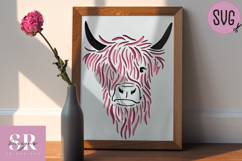 Puede incluir: Una silueta de cabeza de vaca Highland rosa y negra con un dise&ntilde;o detallado y en capas. La imagen est&aacute; enmarcada en un marco de madera natural.