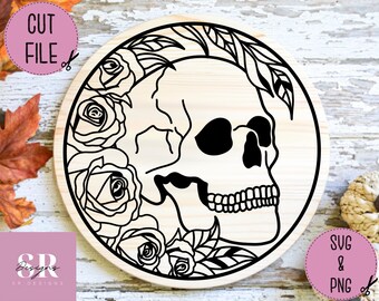 May include: A round wooden sign featuring a black skull design with roses and leaves. The words "CUT FILE" and "SVG & PNG" are in the upper left and lower right corners, respectively. The sign has a natural wood grain background.