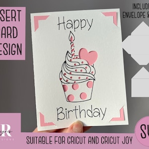 May include: A pink and white cupcake with a candle and a heart on top. The text "Happy Birthday" is written on the card. The card is designed for use with a Cricut cutting machine.