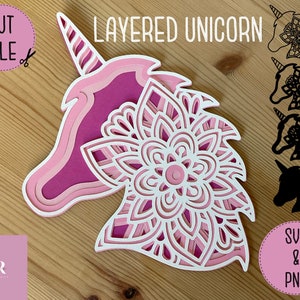 May include: Layered papercraft unicorn design featuring a pink and white mandala pattern. The design is ready to be cut and assembled. The image also includes black and white silhouette versions of the unicorn.