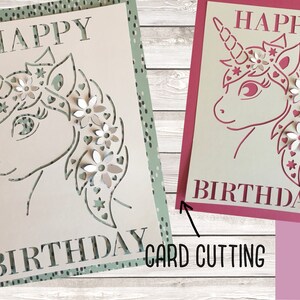 May include: Two handmade paper cards with a unicorn design. The card on the left has a green background with white polka dots and the card on the right has a pink background. Both cards say "Happy Birthday" and feature a unicorn with flowers in its mane.