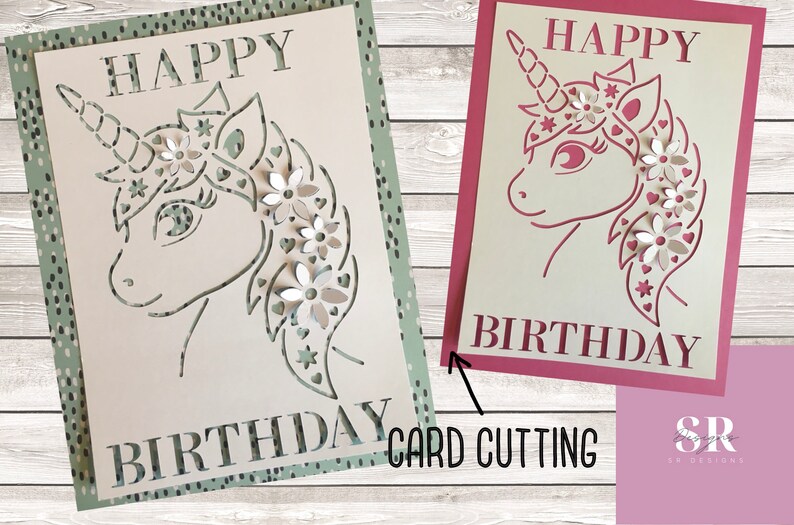 May include: Two handmade paper cards with a unicorn design. The card on the left has a green background with white polka dots and the card on the right has a pink background. Both cards say "Happy Birthday" and feature a unicorn with flowers in its mane.