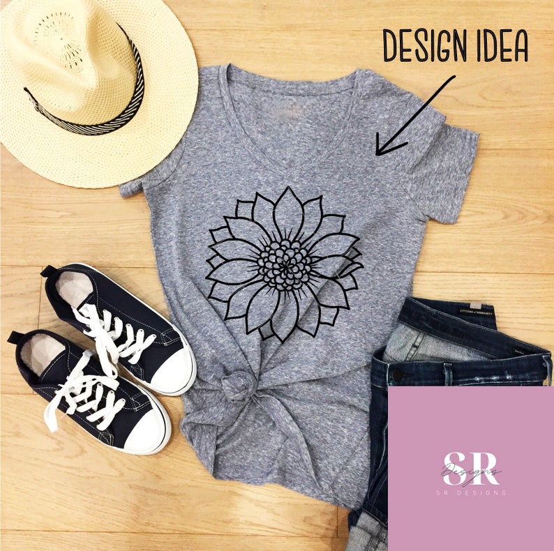 May include: Gray V-neck t-shirt with a black outline of a sunflower design. The shirt is shown on a wooden surface with a straw hat, jeans, and sneakers.