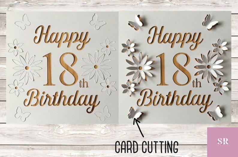 May include: A white card with the words "Happy 18th Birthday" cut out in a wood-like pattern. The card is decorated with white paper flowers and butterflies.