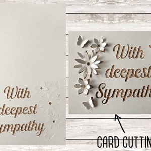 以下が含まれることがあります： 装飾的なフォントで「With deepest sympathy」という文字が切り抜かれた白いカード。カードは、切り抜かれた花と蝶で囲まれています。