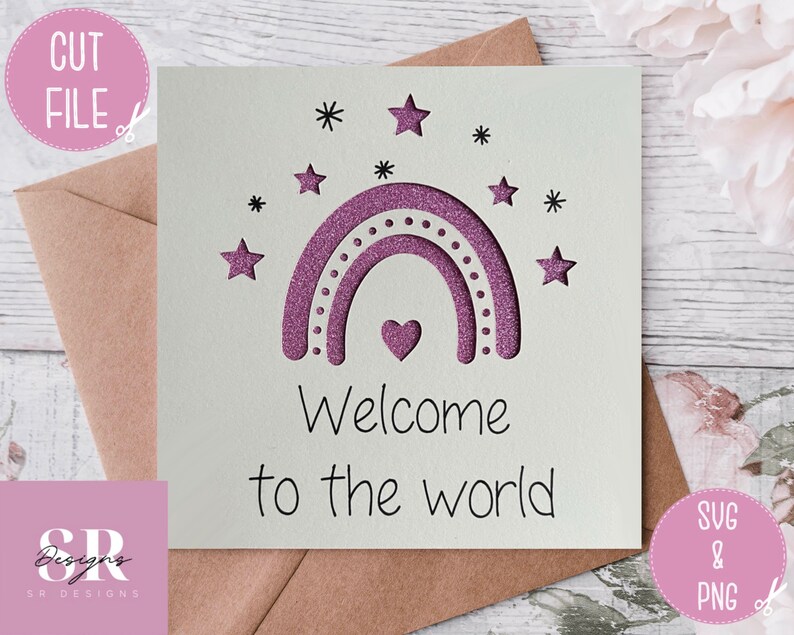 May include: A white card with a pink glitter rainbow and stars. The text "Welcome to the world" is written below the rainbow.