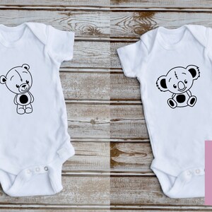 May include: Two white baby onesies with black and white cartoon animal designs. The onesie on the left features a bear and the onesie on the right features a koala.