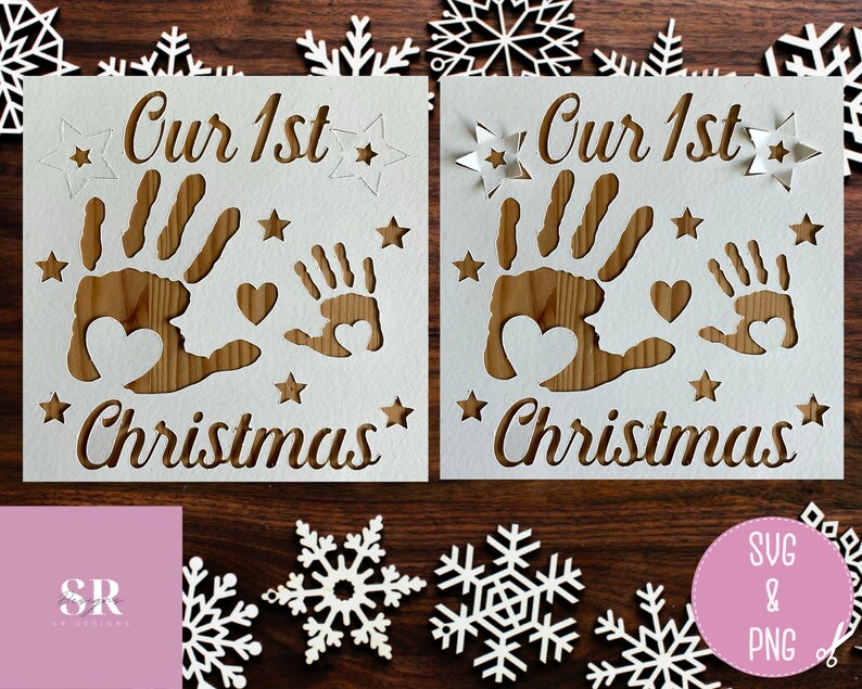 May include: Two white cards with the text "Our 1st Christmas" and a handprint design. The cards are on a wooden surface with white snowflakes.